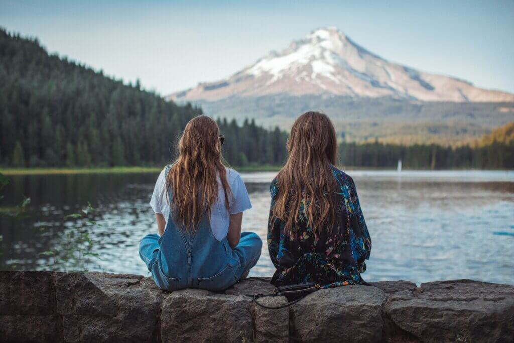 Deux jeunes filles assises face à la montagne.