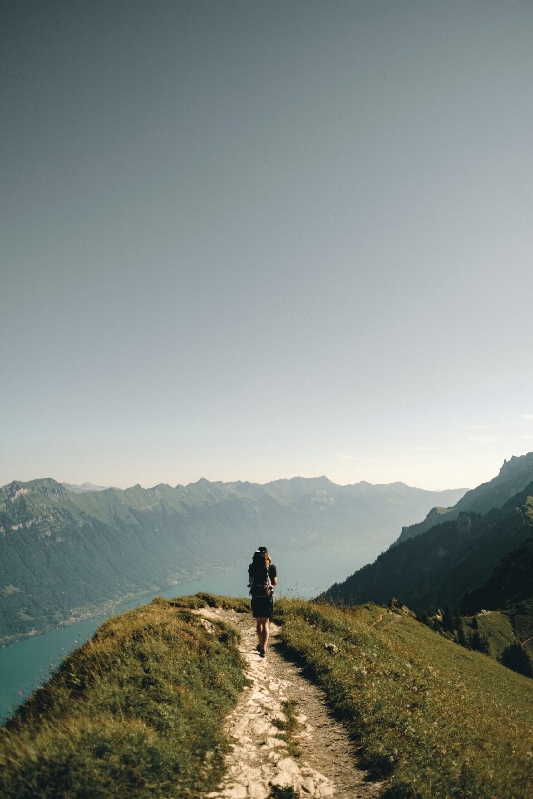 Un randonneur sur un chemin de montagne avec une vue sur un lac.